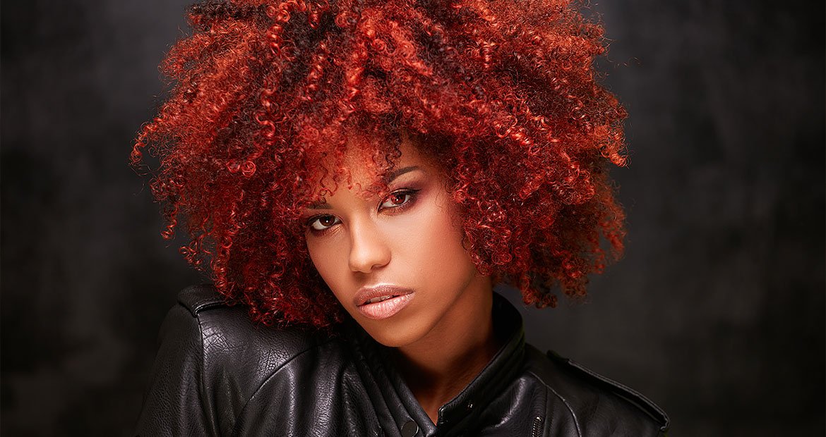 Mulher com o cabelo cacheado em tom ruivo escuro